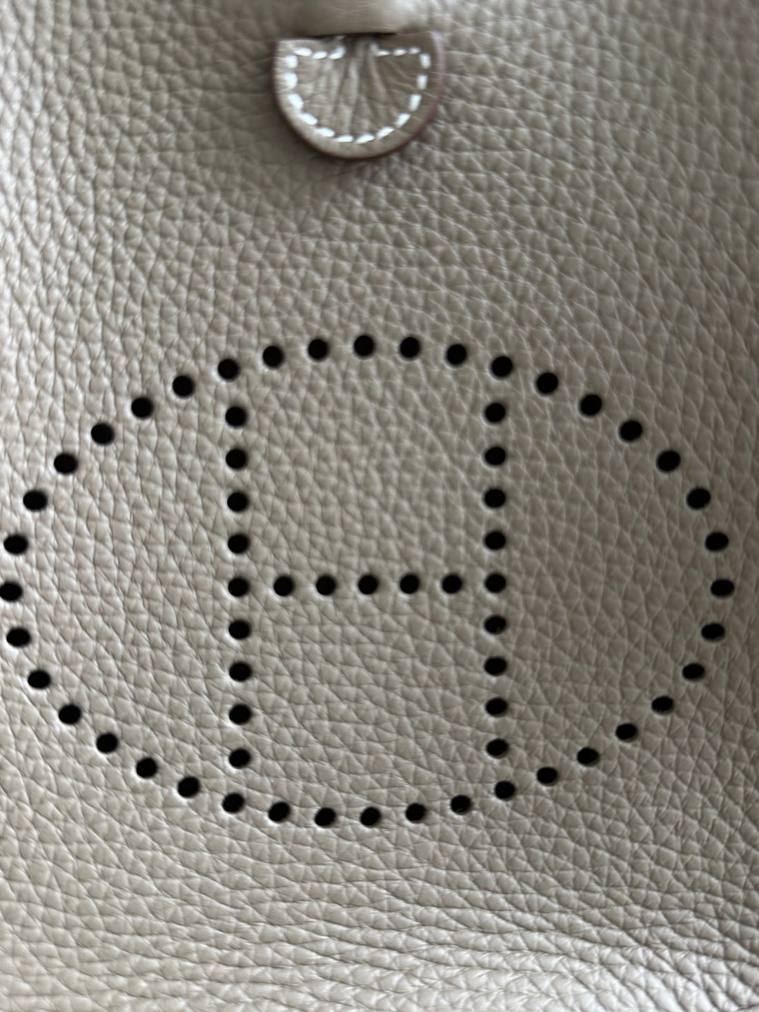 Hermès Evelyne 16 Amazone in der Farbe Etoupe mit dem charakteristischen perforierten „H“-Logo und einem kontrastierenden Schulterriemen in der Farbe bleu/indigo.