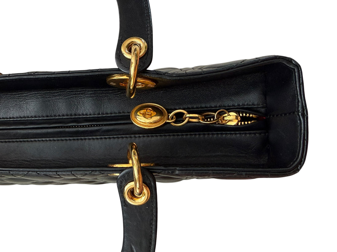 Christian Dior Lady aus schwarzem Lammleder mit Cannage Ziernähten sorgt mit seiner unverkennbaren Steppoptik für einen hohen Wiedererkennungswert. D.I.O.R. Metallanhänger mit Gold-Finish