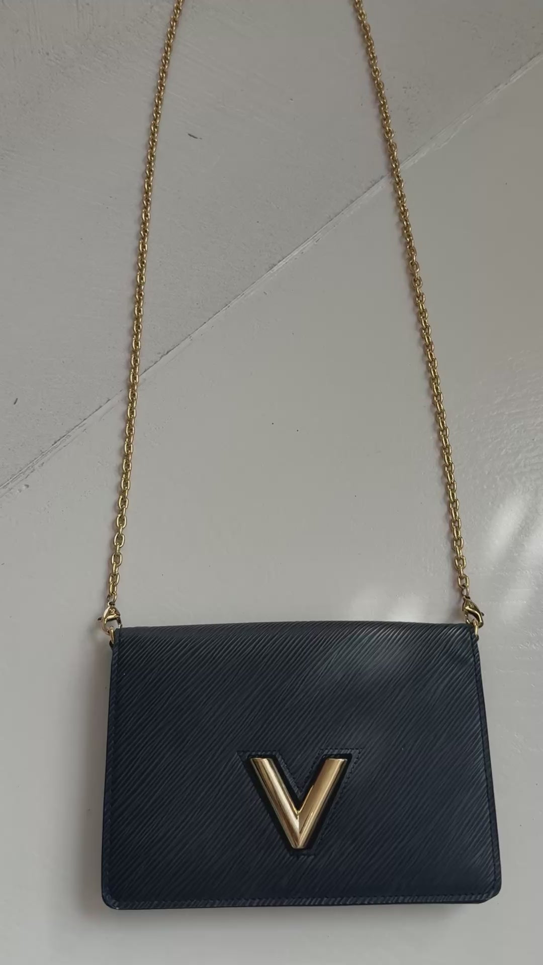 Louis Vuitton Twist Chain Wallet aus schwarzem Epi-Leder mit einem markanten, goldfarbenen LV-Drehverschluss.
